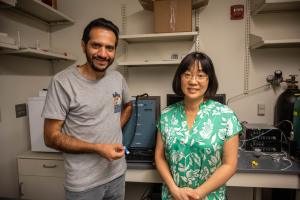 Mohammad Hossein Saberi holds a sensor while standing next to Xiangqun Zeng stand in a lab