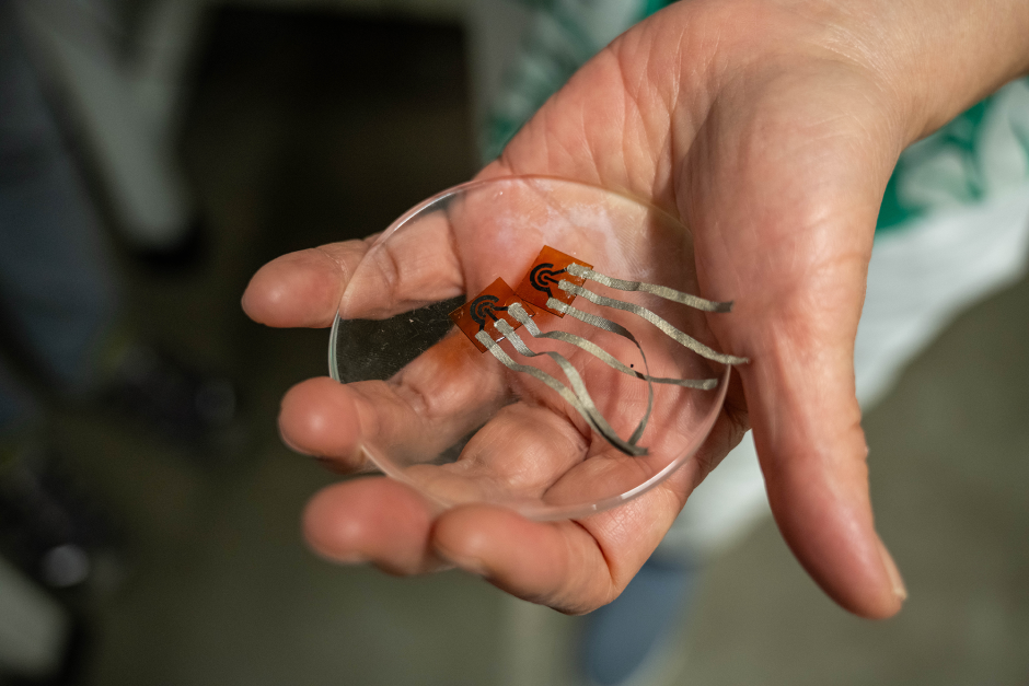 Close up of a hand holding a clear, round sensor